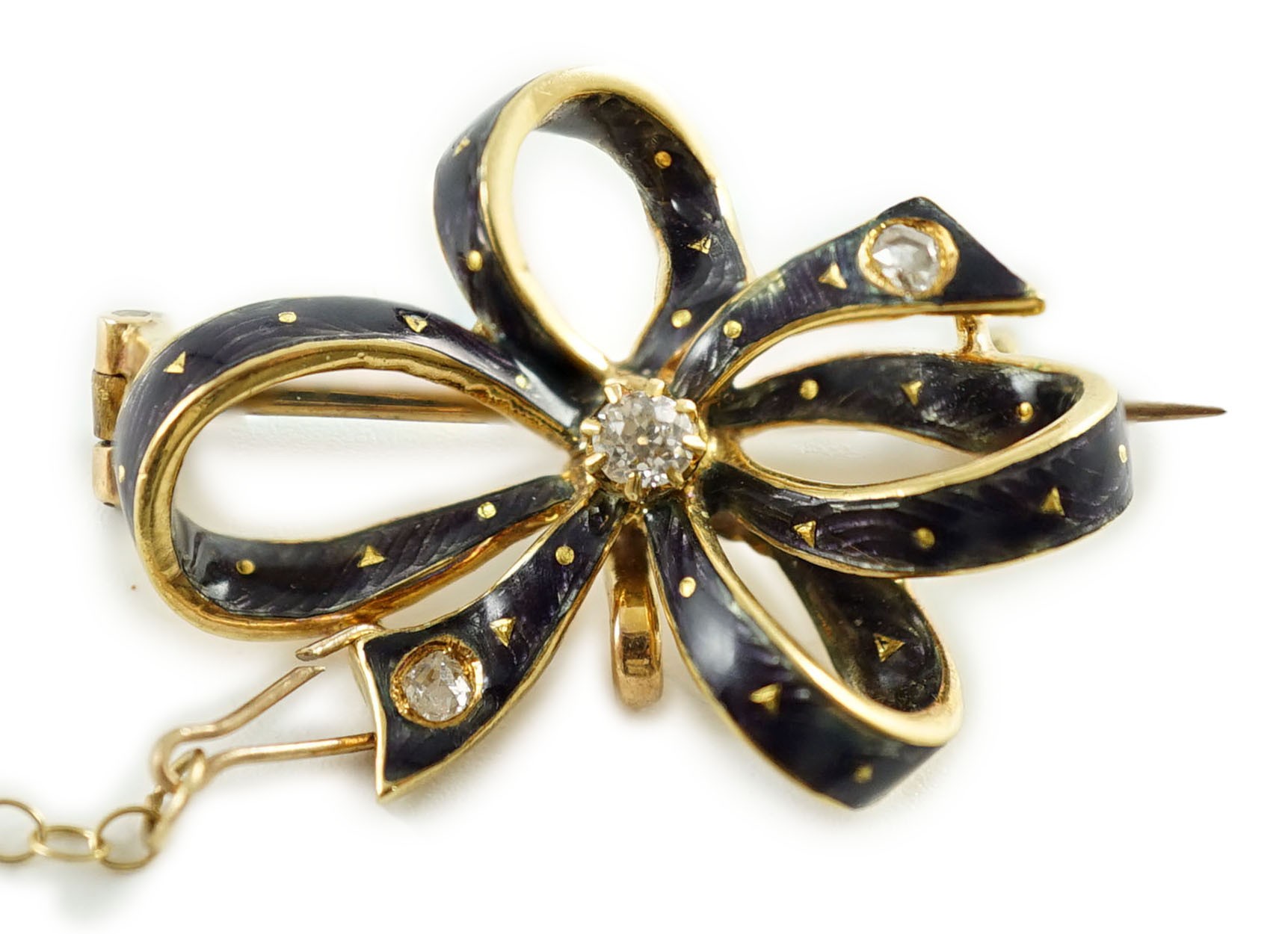 An early to mid 20th century gold, enamel and three stone diamond set ribbon bow brooch